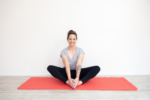 woman in yoga sitting pose on mat in studio - Australian Stock Image