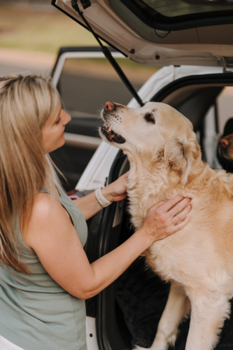 Woman petting her dog in the car boot. - Australian Stock Image