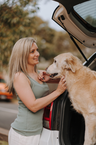 Woman petting her dog in the car boot. - Australian Stock Image