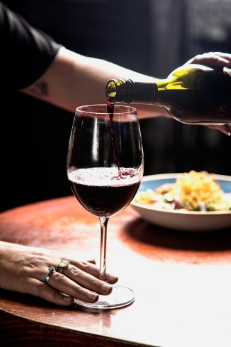 Woman pouring a glass of red wine - Australian Stock Image