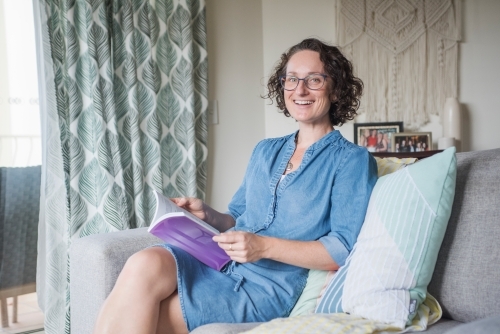 Woman reading book looks at camera - Australian Stock Image