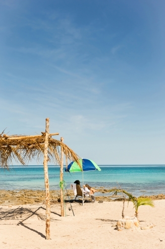 Woman relaxing under beach umbrella on the coast - Australian Stock Image