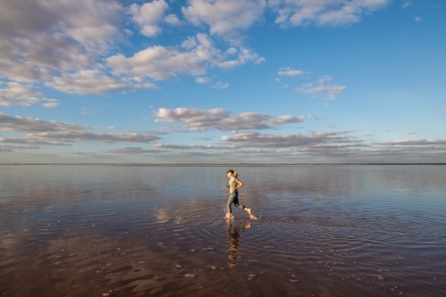 Woman running along on the top of a salt lake. - Australian Stock Image