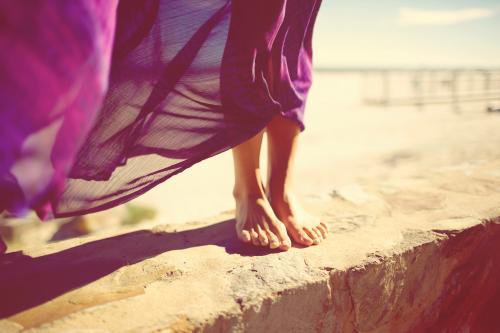 Woman's feet on a wall at a beach - Australian Stock Image