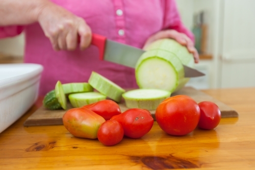 Woman's hand cutting vegetables - Australian Stock Image