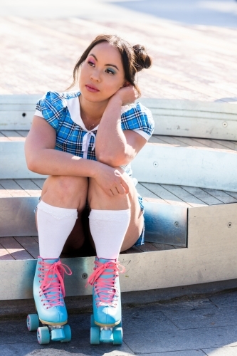 woman sitting down, wearing roller skates - Australian Stock Image