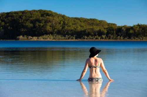 Woman sitting in water of a shallow lake on Fraser Island - Australian Stock Image