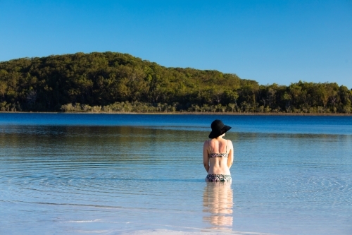 Woman sitting in water of a shallow lake on Fraser Island - Australian Stock Image