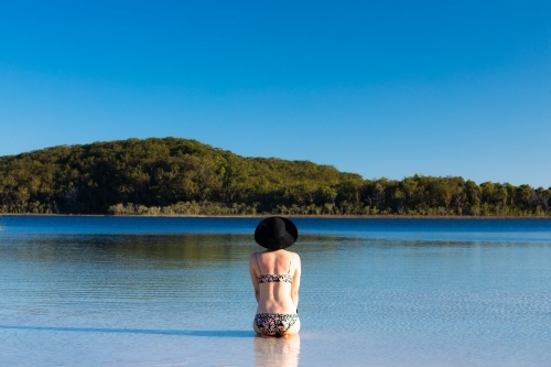 Woman sitting in water of a shallow lake on Fraser Island