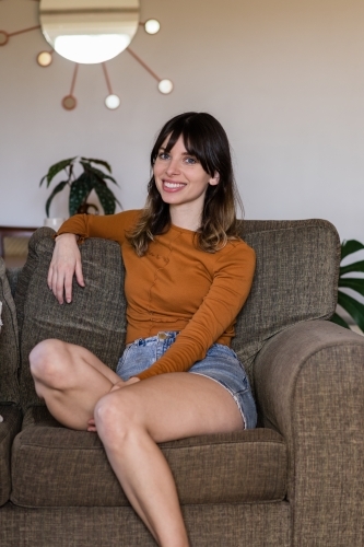 woman sitting on sofa at home - Australian Stock Image