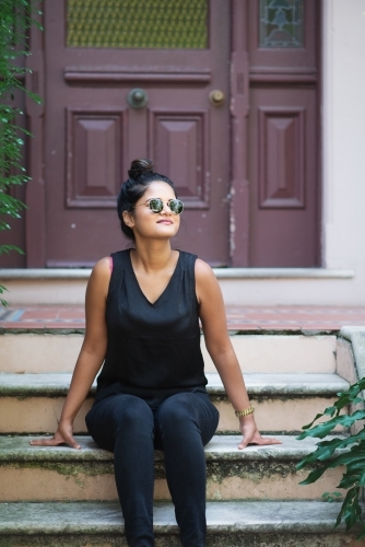 woman sitting on stairs outside old house in inner city Sydney - Australian Stock Image