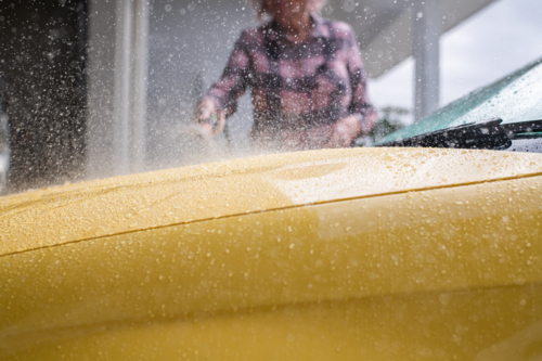 woman spraying car during carwash - Australian Stock Image