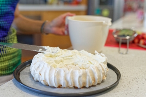 Woman spreading the cream onto the traditional Australian Pavlova - Australian Stock Image
