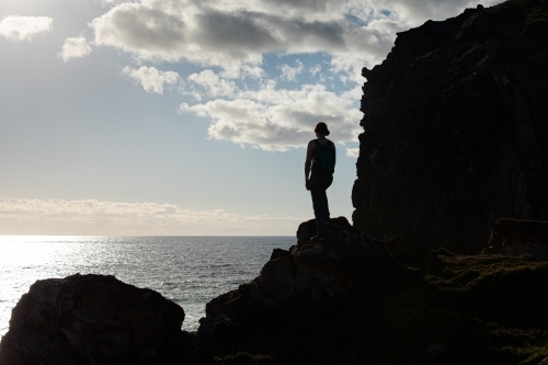 Woman standing on dark rocky outline by the sea