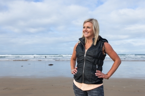 woman standing with hands on hips at the beach - Australian Stock Image