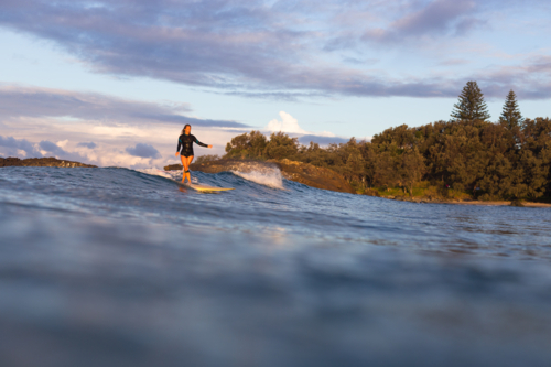 Woman surfing on an ocean wave a Malibu at sunset - Australian Stock Image