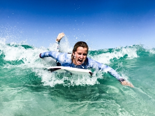 Woman surfing wave on a boogie board in clear ocean - Australian Stock Image