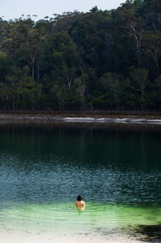 Woman swimming in a forest lined lake on Fraser Island - Australian Stock Image