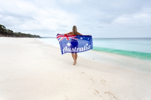 Woman walking along the beach holding Australian Flag