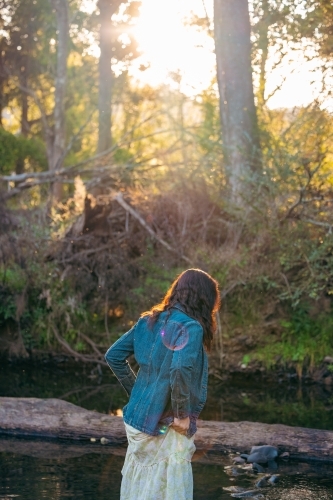 Woman wearing dress walking through creek bed on bush walk - Australian Stock Image