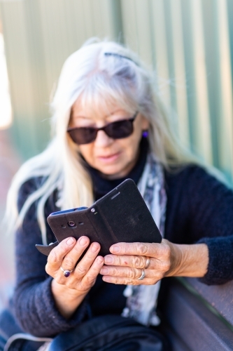 Woman wearing sunglasses looking at smartphone - Australian Stock Image