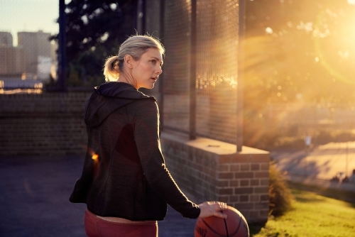 Woman with basketball in sunlight - Australian Stock Image