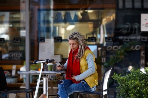 Woman with dreadlocks at cafe with electric scooter - Australian Stock Image