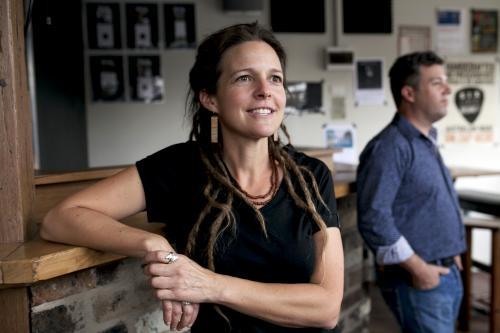 Woman with dreadlocks leaning against bar at local craft beer pub - Australian Stock Image