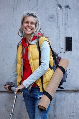 Woman with dreadlocks on electric scooter going to her yoga class - Australian Stock Image