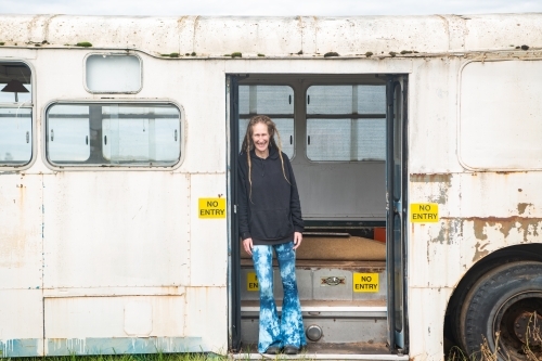 Woman with dreadlocks standing on steps of bus exit. - Australian Stock Image