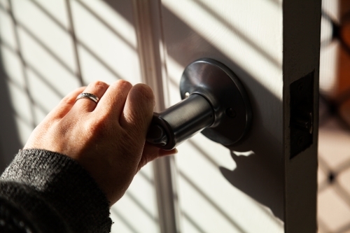 Woman with wedding rings on her finger unlocking front door - Australian Stock Image