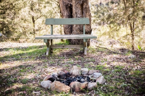 Wooden bench seat in bush with camp fire - Australian Stock Image