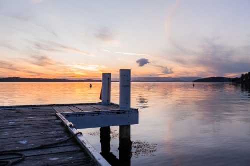 wooden jetty posts in lake water in pastel dusk light Cams Wharf, Newcastle, NSW, Australia - Australian Stock Image