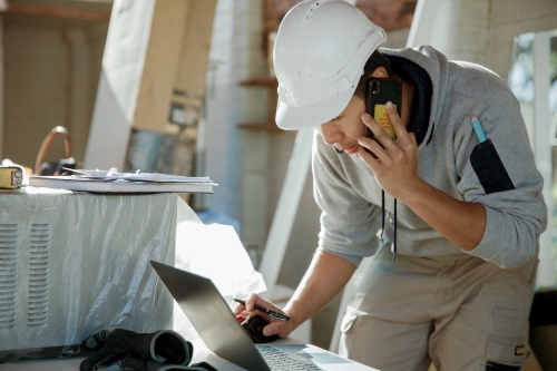 Worker checking building details on a construction site - Australian Stock Image