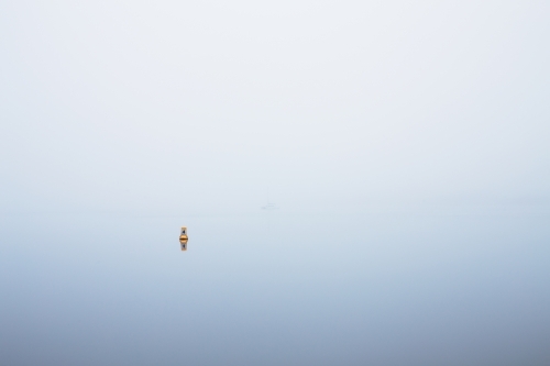 yellow marker buoy on foggy river - Australian Stock Image