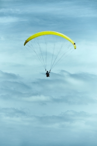 Yellow paraglider in a cloudy and moody sky - Australian Stock Image