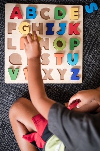 Young Aboriginal boy doing a letter puzzle - Australian Stock Image