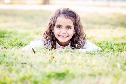Young aboriginal girl laying in grass smiling