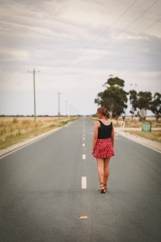 Young adult woman down empty rural road - Australian Stock Image