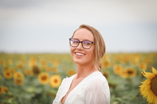 Young adult woman standing in sunflower field - Australian Stock Image