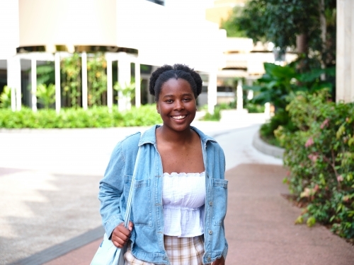 Young African woman walking with a tote bag on a university campus - Australian Stock Image