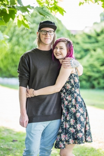 Young alternative couple cuddling smiling - Australian Stock Image