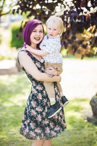 Young alternative mum holding young child with arms around neck