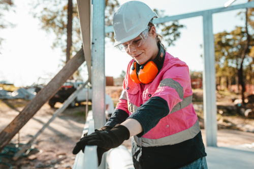 Young apprentice using a leveller on the metal framework. - Australian Stock Image