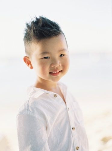 Young Asian boy outside, smiling at the camera - Australian Stock Image