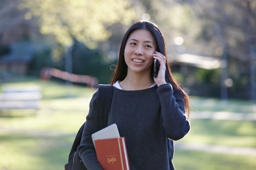 Young Asian female university student on mobile phone - Australian Stock Image