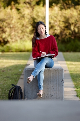 Young Asian female university student studying outdoors - Australian Stock Image