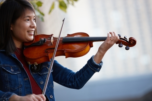 Young Asian female violin player practising outdoors - Australian Stock Image