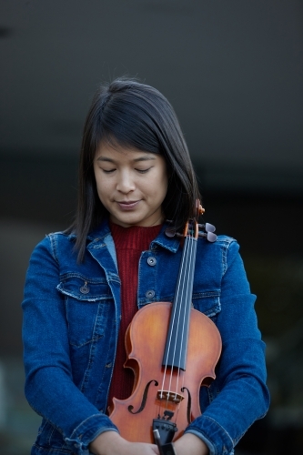 Young Asian female violin player practising outdoors - Australian Stock Image