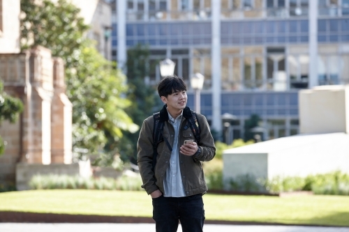 Young Asian university student using mobile phone on-campus - Australian Stock Image